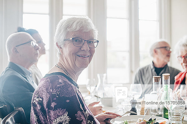 Portrait of senior woman smiling while sitting by friends in restaurant