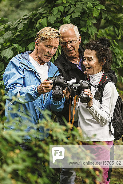Älterer Mann zeigt einer Ausbilderin und Freundin die Kamera während eines Fotokurses