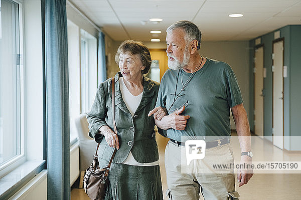 Älteres Ehepaar geht Arm in Arm im Altenpflegeheim