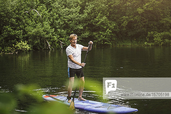 Seniormann paddelt auf See während eines SUP-Kurses