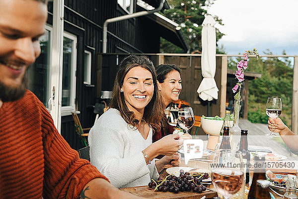 Smiling woman looking at friend while enjoying during dinner in party