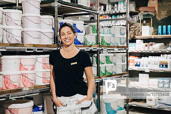 Porträt einer lächelnden Verkäuferin mit Händen in der Tasche im Laden stehend