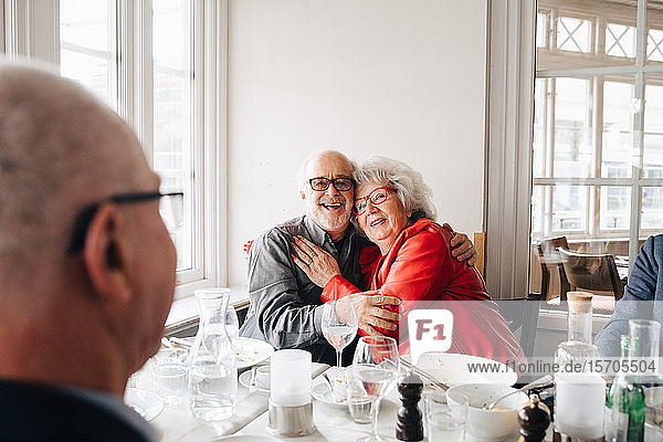 Älterer Mann umarmt Frau  während er im Restaurant sitzt