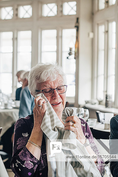 Senior woman crying while sitting in restaurant