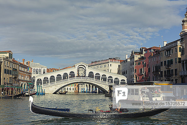 A gondola crossing the Grand Canal with a vaporetto and the Rialto Bridge beyond  Venice  UNESCO World Heritage Site  Veneto  Italy  Europe