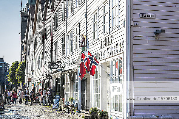 Touristen sehen sich Geschäfte und traditionelle Holzhäuser in der alten Straße Bryggen an  Bergen  Provinz Hordaland  Norwegen  Skandinavien  Europa