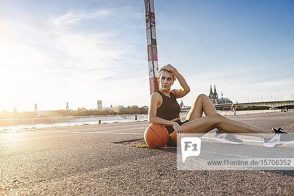Blonde Frau sitzt mit Basketball auf einem Spielfeld in Köln  Deutschland