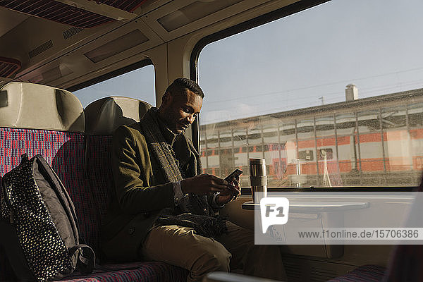 Stylish man using smartphone inside a train