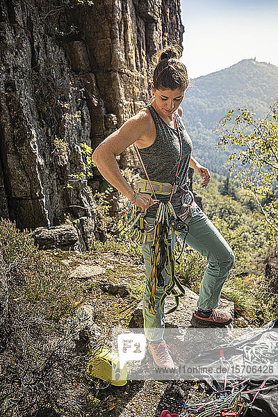 Woman preparing to climb  putting on climbing harness