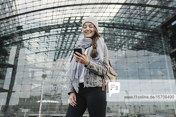 Glückliche junge Frau mit Smartphone am Hauptbahnhof  Berlin  Deutschland