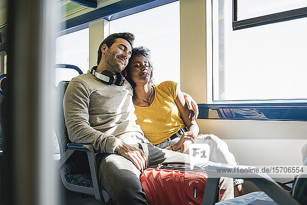 Junges Paar mit geschlossenen Augen entspannt sich in einem Zug
