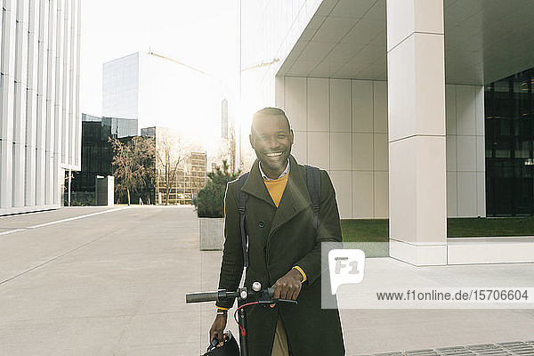 Portrait of happy man with scooter in the city