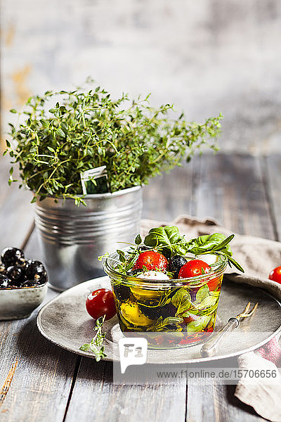 Topfthymian und in Olivenöl eingelegter frischer Caprese-Salat in Gläsern