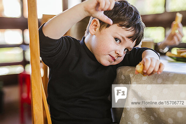 Portrait of a boy eating churros at table at home