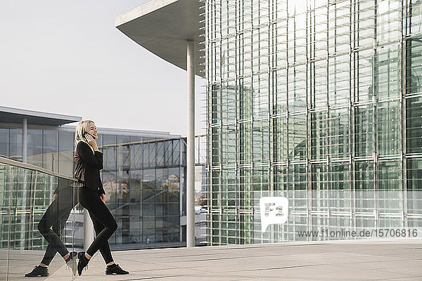 Blond businesswoman using smartphone in the background modern buildings