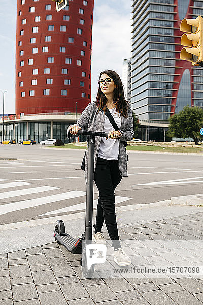 Young businesswoman walking with e-scooter in the city