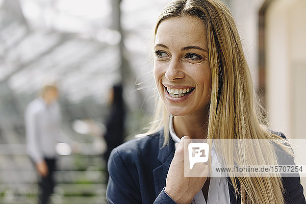 Porträt einer glücklichen jungen Geschäftsfrau im Amt mit Kollegen im Hintergrund