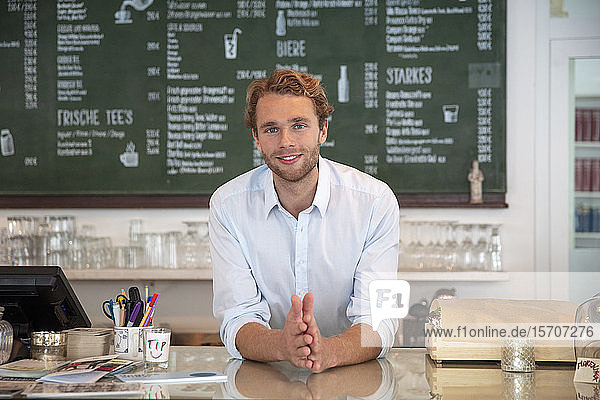 Junger Geschäftsmann in einem Café an den Tresen gelehnt