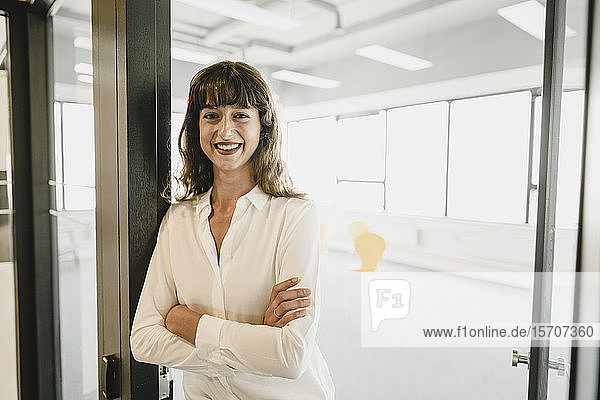 Smiling businesswoman standing in an open office door