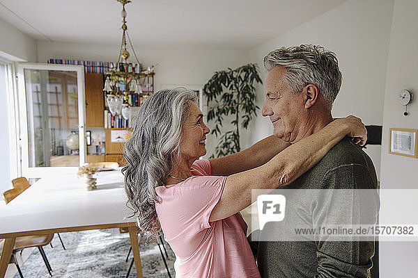 Glückliches älteres Paar umarmt sich zu Hause im Wohnzimmer