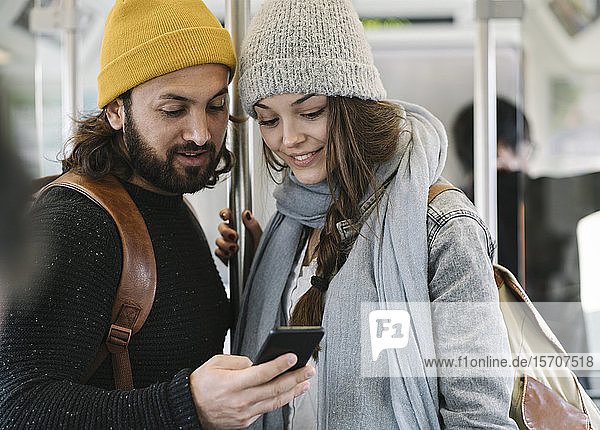 Junges Paar benutzt Smartphone in der U-Bahn