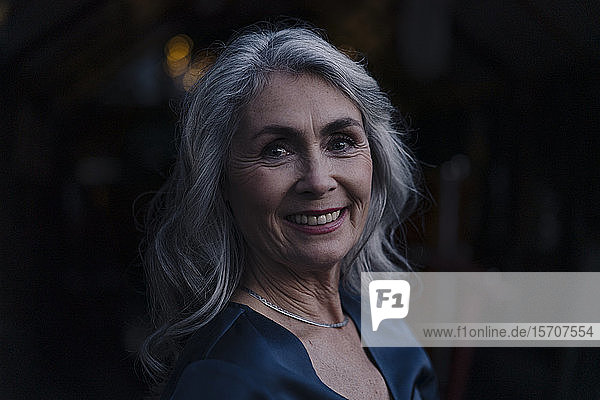 Porträt einer lächelnden reifen Frau im Freien bei Nacht