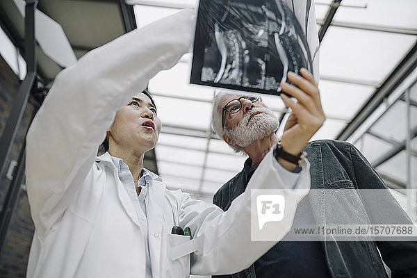 Weibliche Ärztin bespricht Röntgenbild mit älterem Patienten
