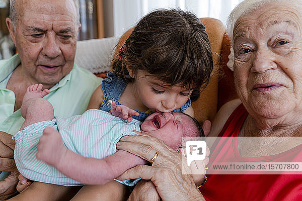 Großeltern mit kleinem Mädchen und Neugeborenem zu Hause