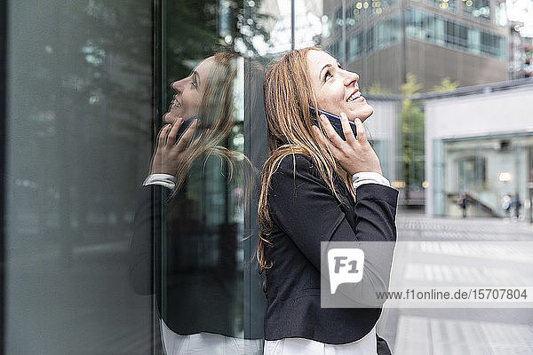 Lächelnde Geschäftsfrau am Telefon in der Stadt