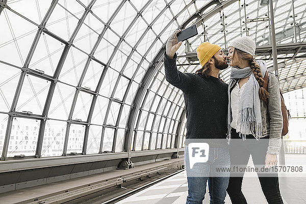 Young couple kissing and taking a selfie at the station platform  Berlin  Germany