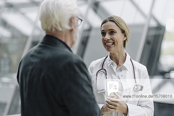 Lächelnde Ärztin im Gespräch mit älterem Mann