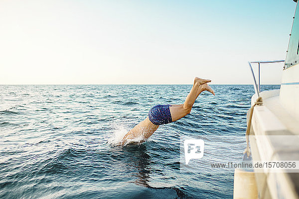 Junger Mann springt aus einem Boot ins Meer