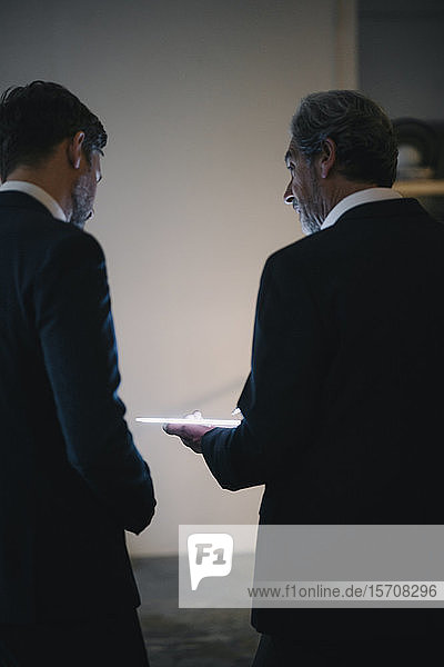 Zwei Geschäftsleute mit leuchtender Tafel reden im Büro