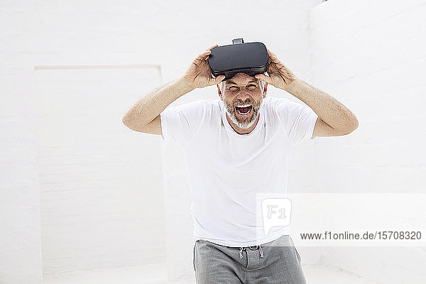 Reifer Mann mit VR-Brille  schaut in die Kamera  lacht
