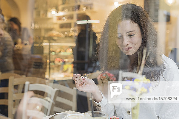 Smiling young woman eating cake in a cafe