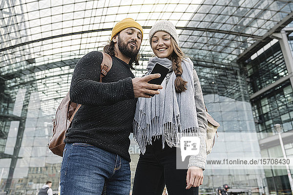 Glückliches junges Paar mit einem Smartphone am Hauptbahnhof  Berlin  Deutschland