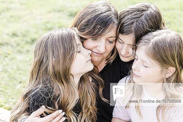 Glückliche Mutter mit drei Drillings-Töchtern auf einer Wiese