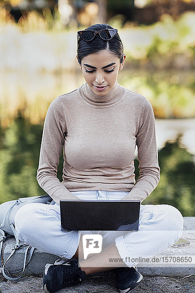Junge Frau benutzt Laptop im Freien