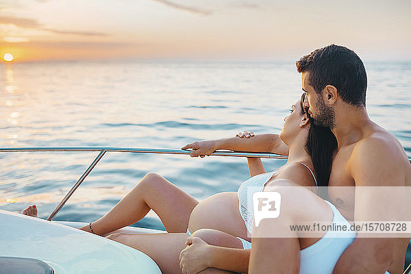 Romantisches Paar mit schwangerer Frau auf Boot sitzend