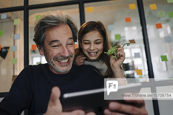 Glücklicher Gelegenheits-Senior-Businessmann und Mädchen benutzen Tablet im Büro