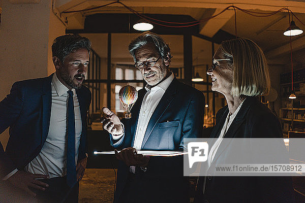 Geschäftsleute mit glänzender Tablette und schwebendem Heißluftballon im Büro