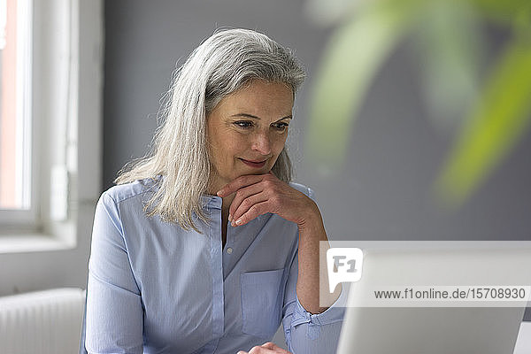 Portrait einer reifen Geschäftsfrau mit Laptop im Büro