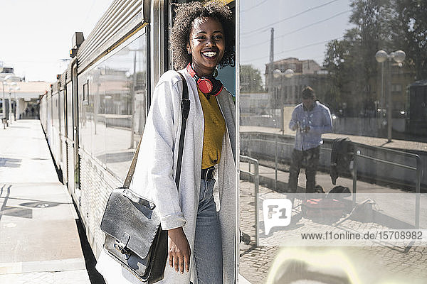 Happy young woman entering a train