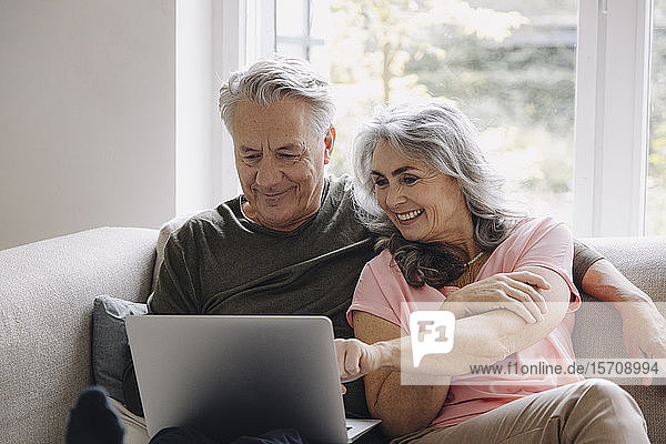 Glückliches älteres Ehepaar mit Laptop zu Hause auf der Couch