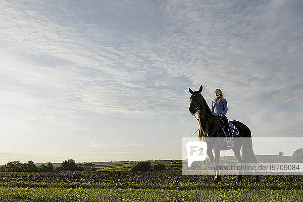 Frau zu Pferd auf einem Feld auf dem Land