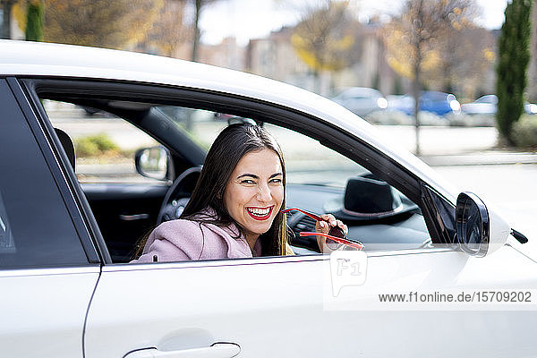 Lächelnde Geschäftsfrau mit Sonnenbrille im Auto
