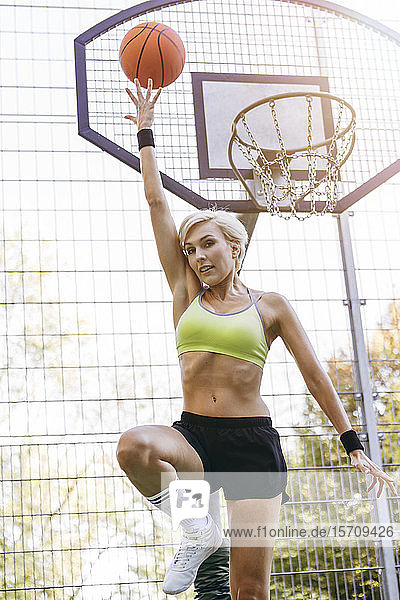 Blonde woman playing basketball  dunking