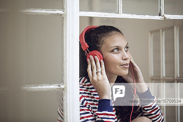 Young woman at the window listening to music