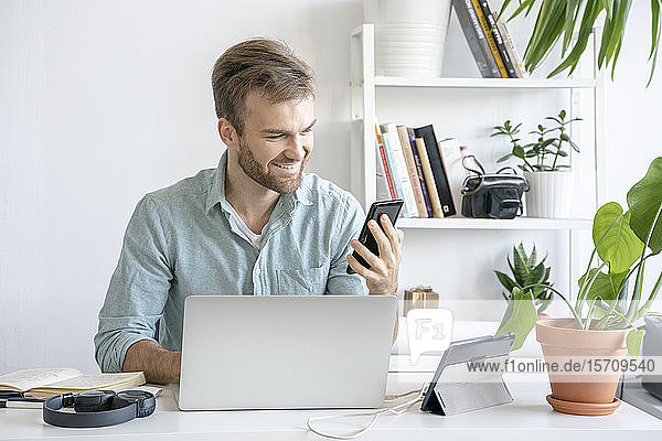 Smiling man using smartphone at desk in office