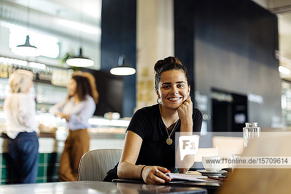 Young woman sitting in bistro  reading magazine